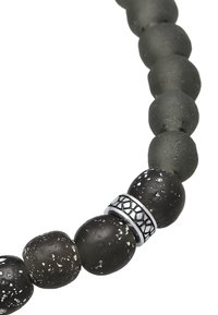 Bracciale con perline che presenta perline opache nere e grigie, con uno spacer decorativo in tonalità argento. Le perline variano per consistenza e finitura.