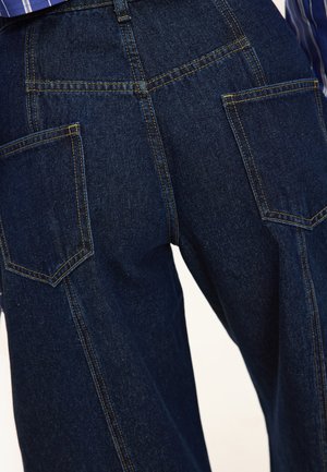 Dark blue denim wide-leg pants with two back pockets and contrast stitching. The fabric has a smooth texture and structured design.