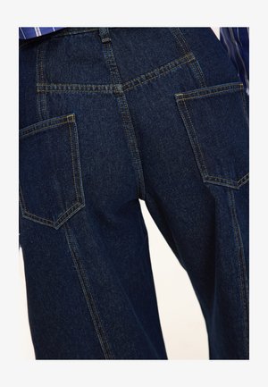 Dark blue denim wide-leg pants with two back pockets and contrast stitching. The fabric has a smooth texture and structured design.