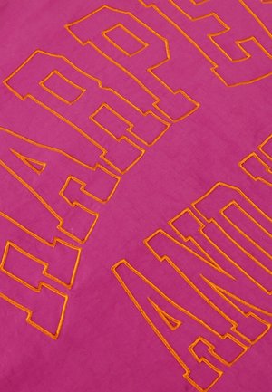 Roze stof met gewaagd oranje geborduurde tekst, met een gladde textuur en een vlakke lay-out. De letters hebben een dikke, blokachtige vorm.