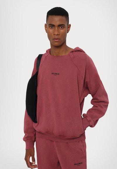 Sweatshirt em tons de bordeaux desbotado, com mangas longas, bolso canguru e capuz ajustável. Apresenta a palavra "SILÊNCIO" impressa em preto no peito.