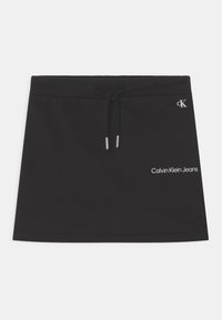 Musta puuvillainen mini-hame, jossa on nauhavyötärö. Takataskussa pieni hopea-logo ja teksti "Calvin Klein Jeans" valkoisella. Sileä pinta.