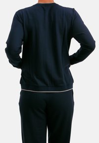 Top de manga larga en azul marino con cuello y puños acanalados, con una textura lisa. La prenda tiene un diseño ajustado y dobladillo elástico.