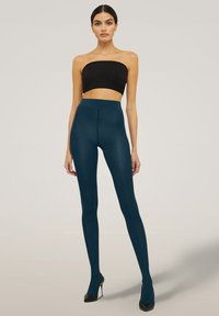 Leggings a vita alta color verde acqua realizzati in materiale elastico, con una texture liscia e un design aderente, abbinati a un crop top nero.