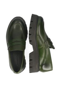 Par de mocasines de cuero verde oscuro con suelas negras chunky y estriadas, uno mostrado desde arriba y el otro de lado.