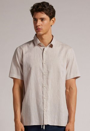 Short-sleeve, light beige button-up shirt with subtle texture and horizontal stripes. Features a classic collar and six buttons down the front.