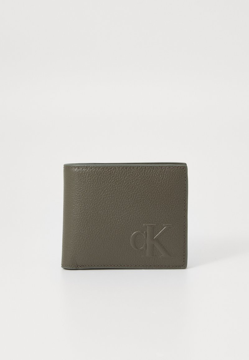 Portafoglio in pelle verde oliva con finitura texture, logo "cK" impresso sul davanti e design a due pieghe. Stile minimalista.