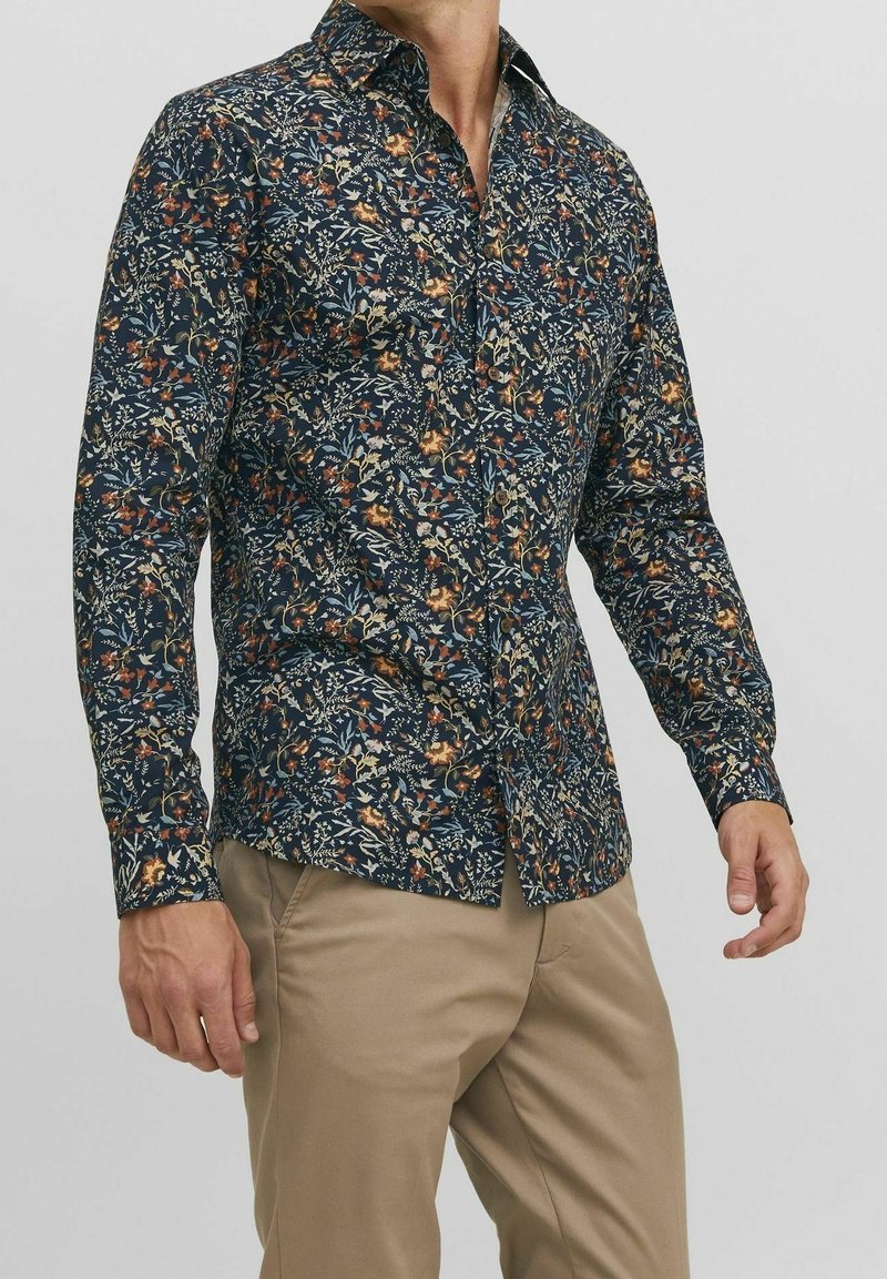 Camisa abotonada con base azul marino y estampado floral en tonos naranja, amarillo y crema. Manga larga, corte regular y cuello.