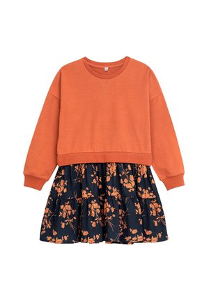 Orange sweatshirt med lange ærmer kombineret med et marineblåt skørt med et orange blomstermønster og trinvise flæser ved kanten.