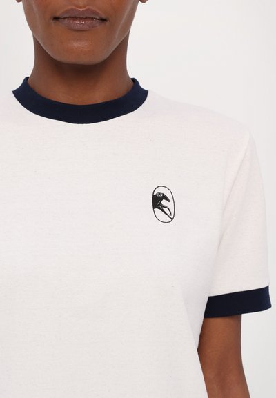 Cotton t-shirt in off-white with navy ribbed neckline and sleeve cuffs. Features a small black embroidered logo of a horse inside an oval.
