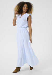 Robe rayée bleu clair avec des manches à volants, un décolleté en forme de clé et une jupe à plusieurs niveaux. Elle présente une taille cintrée et une silhouette fluide.