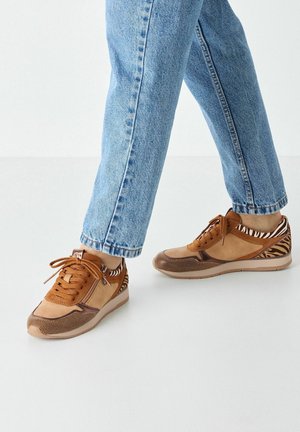 Brown mixed-material sneakers featuring a textured toe cap, contrasting side accents, and a subtle zebra stripe pattern on the heel.
