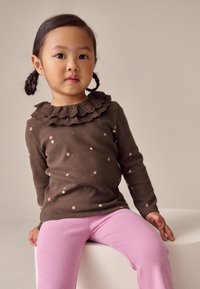 Ruskea pitkähihainen paita, jossa hupullinen kaulus ja värikkäitä pilkkuja, yhdistetty vaaleanpunaisiin ribbineulottuihin legginsseihin. Yksinkertainen ja mukava istuvuus.