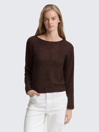 Brązowy sweter z dzianiny o szerokim dekolcie, długimi rękawami i luźnym kroju, w połączeniu z białymi spodniami z wysokim stanem. Miękka tekstura.