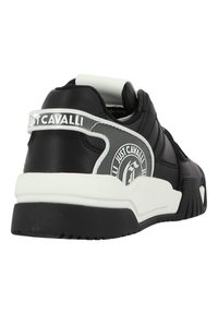 Basket noire avec une finition en cuir lisse, semelle blanche, logo bien en vue et panneaux texturés contrastés sur le dessus.