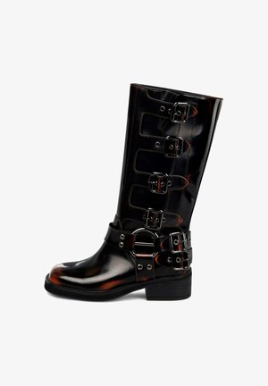 Cizme negre din piele lacuită, până la genunchi, cu cinci curele cu catarame reglabile și talpă joasă, având o textură netedă și lucioasă.