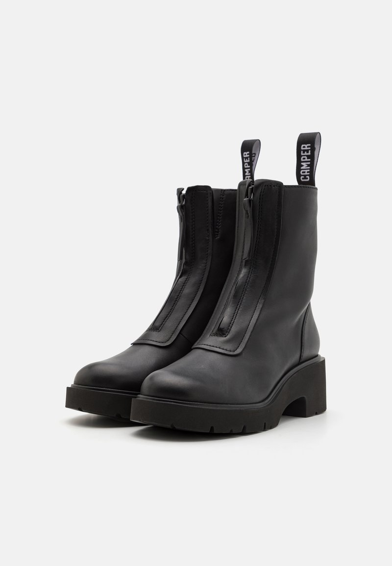 Schwarze Leder-Stiefeletten mit glatter Oberfläche, ausgestattet mit einer dicken Plateausohle, einem Reißverschluss vorne und einer Zuglasche mit der Aufschrift "Camper".