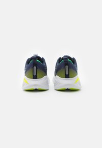 Scarpe sportive blu navy e verde lime con tomaia in rete, colletto imbottito, suola bianca e dettagli riflettenti sul tallone.