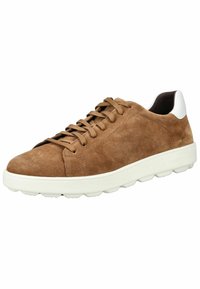 Baskets en daim marron avec des accents blancs, lacets plats, bout rond et une semelle en caoutchouc blanc épaisse avec des bords arrondis.