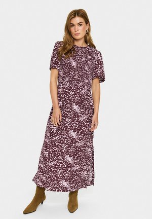 Bordeauxfarbenes Midi-Kleid mit weißem Punktmuster, kurzen Puffärmeln und elastischem Bund. Kombiniert mit braunen Wildleder-Stiefeletten.