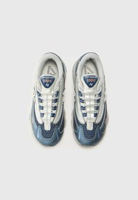 Des baskets New Balance bleu et argent présentent un design en mesh et synthétique, une toe arrondie, des coutures décoratives et une semelle texturée.