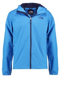 Blå lättviktsregnjacka med huva, dragkedja fram, elastiska ärmslut och logotyp på vänster bröst. Slät, glänsande tyg, minimalistisk design.