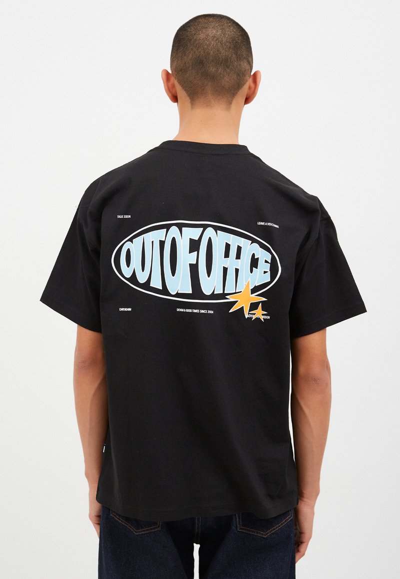 Svart bomulls t-shirt med en stor ljusblå "OUTOFOFFICE" grafik och två gula stjärnor på ryggen. Korta ärmar och avslappnad passform.
