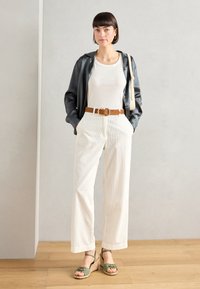 Černá saténová košile, bílý ribbed tílko, béžové široké kalhoty s opaskem a zelené espadrilky. Jednoduché doplňky dokončují vzhled.