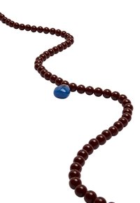 Brązowy okrągły naszyjnik z koralików z niebieskim akcentem w kształcie kropli. Koraliki wyglądają na błyszczące i jednolicie wymiary, nawleczone w płynny, zakrzywiony wzór.