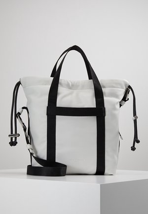 Weiße Ledertasche im Tote-Stil mit schwarzen Griffen, verstellbarem Schulterriemen und Kordelverschlüssen an beiden Seiten.