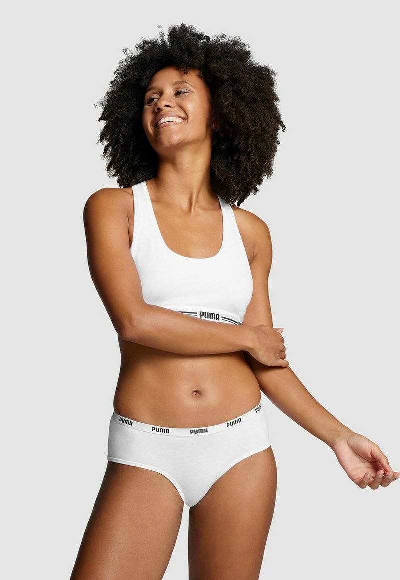 Weißer Sport-BH und passende Unterhose, beide aus weicher Baumwolle, mit schwarzen "Puma"-Logo-Bändern an der elastischen Taille und dem Träger.