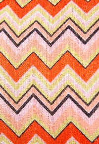 Textil s cikcak vzorem v oranžové, růžové, žluté a černé barvě. Tkanina má texturovaný, pletený vzhled s různými šířkami.