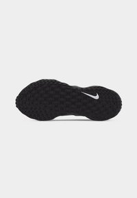 Μαύρη υφασμάτινη σόλα παπουτσιού Nike με λευκό λογότυπο Nike Swoosh κοντά στο κέντρο σε απλό ανοιχτό γκρι φόντο.