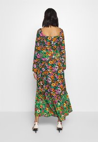 Abito lungo a maniche lunghe con motivo floreale, caratterizzato da uno sfondo nero e vivaci fiori rosa, arancioni e verdi, con un orlo fluente.