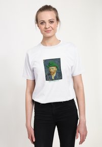 Biała koszulka z portretem mężczyzny w zielonym kapeluszu i napisem "Wesołego Dnia Świętego Patryka" poniżej. Krótkie rękawy, standardowy krój.