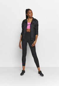 Mustad tõmbluku jao must jakk roosa spordibrassi peal, koos kõrge puusa jope mustade retuuside ja mustade spordijaluudega. Sile, sobiv disain.