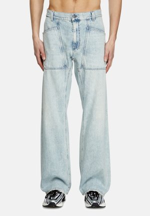 Light blue denim wide-leg jeans with visible stitching, large front pockets, and a relaxed fit. Paired with black and white sneakers.