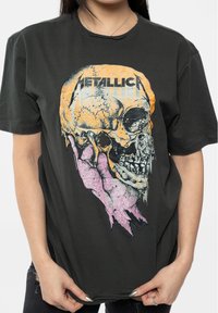 Black cotton t-shirt featuring a large graphic of a skull in orange and pink tones, with the word "METALLICA" printed above.