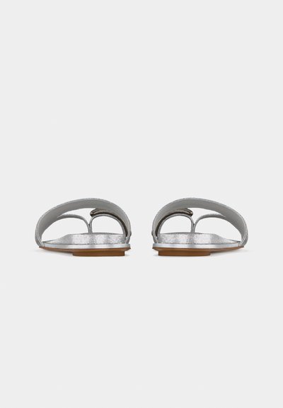 Επίπεδα ανοιχτά ασημένια σανδάλια με δύο οριζόντιες λουρίδες και δαχτυλίδι για τα δάχτυλα, φωτογραφημένα από μπροστά σε λευκό φόντο.