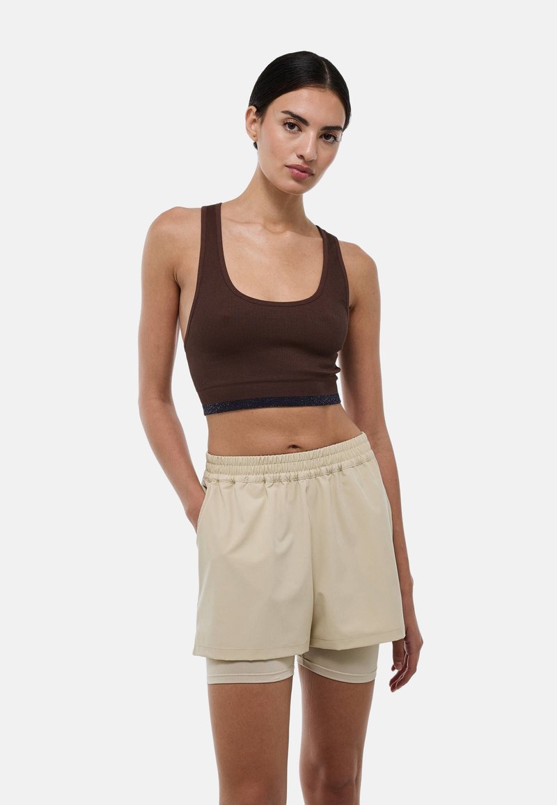 Top court en côtes marron avec une taille bleue marine, associé à un short beige clair avec une taille élastique et des poches. Texture lisse.