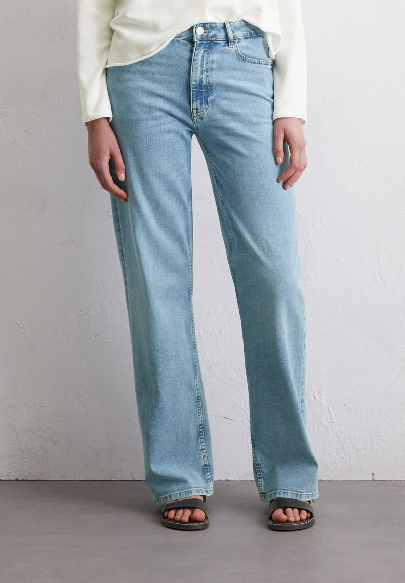 Lichtblauwe denim jeans met een rechte pasvorm, voorzien van een klassiek vijf-pocket ontwerp en subtiele vervagingsdetails. Draag ze met zwarte sandalen.