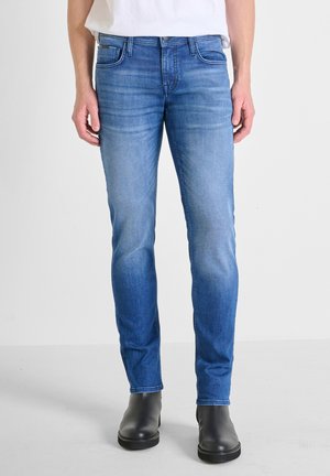 Jeans blu slim-fit con un finish sbiadito, cinque tasche e un design a gamba dritta, abbinati a stivaletti neri alla caviglia.