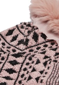 Luddig rosa stickad mössa med svarta geometriska mönster, med ett ribbat band och en fluffig rosa pom-pom på toppen.