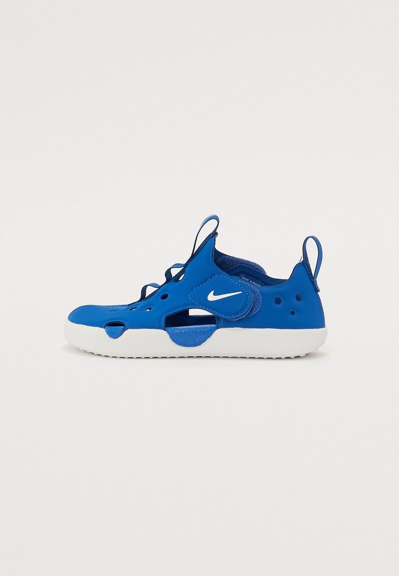 Blue sneaker with a mesh upper and rubber sole. Features cut-out sections, a white logo, and rear pull tab for easy wear.