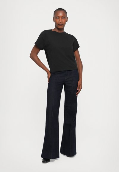 Black short-sleeve t-shirt paired with dark flared jeans. T-shirt has a simple design; jeans feature subtle stitching and a straight cut.