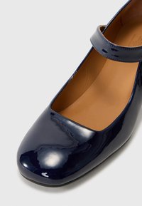 Scarpa Mary Jane in vernice navy con punta quadrata, cinturino alla caviglia e rivestimento interno liscio, caratterizzata da una texture lucida.