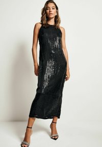 Robe maxi noire pailletée avec une silhouette ajustée, sans manches et à coupe droite. Présente une texture lisse et brillante avec un motif en quadrillage subtil.