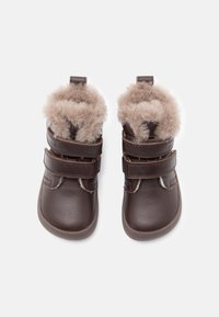 Bruna läderstövlar med dubbla remmar, som har en mjuk foder av päls på toppen och en platt gummisula. Kompakt och rundad design.