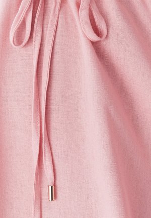 Tissu rose clair avec une surface texturée, présentant un cordon avec un embout en métal. Le tissu tombe doucement.