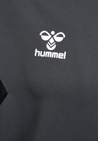 Donkergrijze sportshirt met een gestructureerde stof, met een wit logo en bijenontwerp. Inclusief een zwarte accent in één van de hoeken.